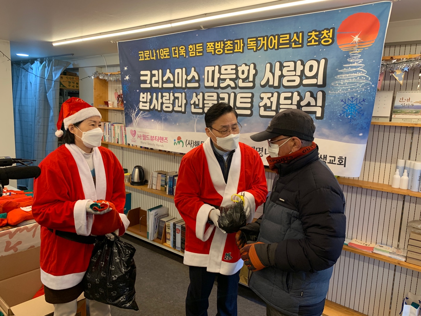 ▲(사)월드뷰티핸즈 최에스더 회장(왼쪽)과 (사)해돋는 마을 장헌일 이사장(가운데)이 이웃에게 선물을 전달하고 있다.
